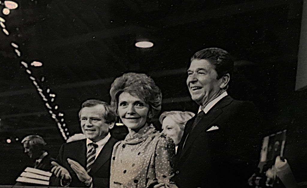 President Ronald Reagan and Nancy Reagan standing on stage in front of the audience at the 1984 RNC in black and white photo.