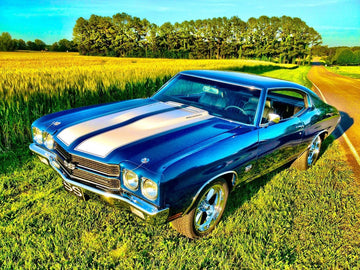 1970 Chevrolet Chevelle SS in vibrant blue with white stripes, parked beside a wheat field