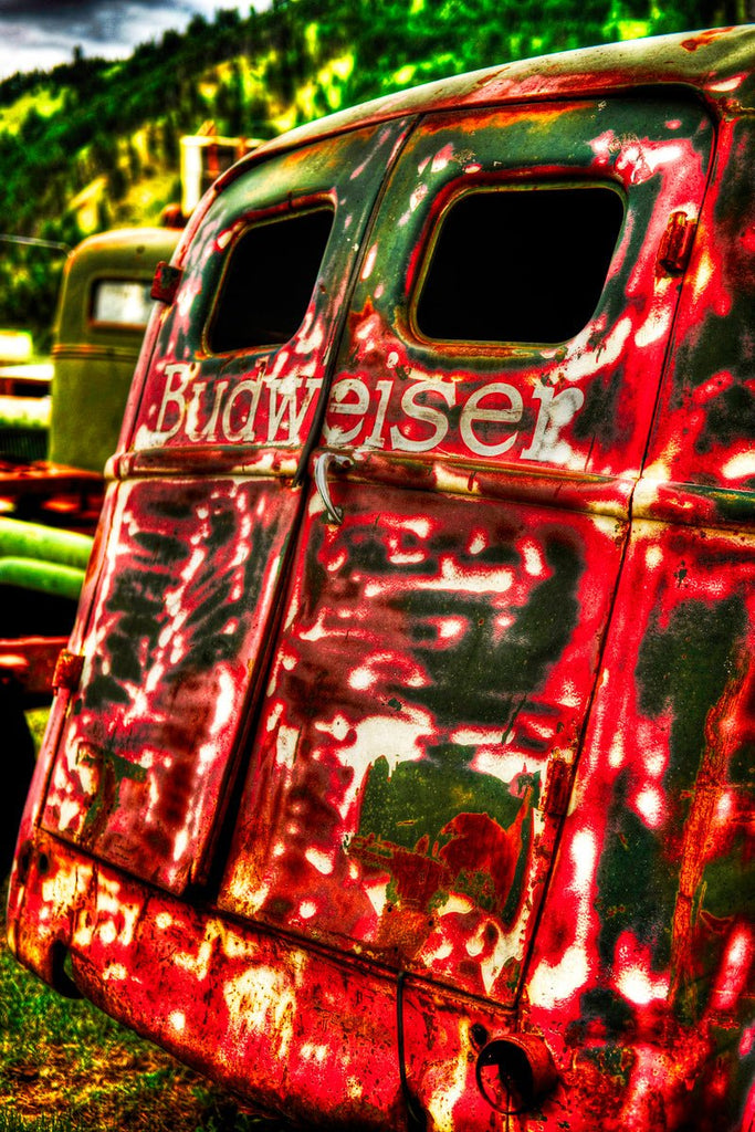 Rusting Budweiser van in Montana’s Big Sky captured by Michael W. Rutherford, with green mountains and blue skies in the background.