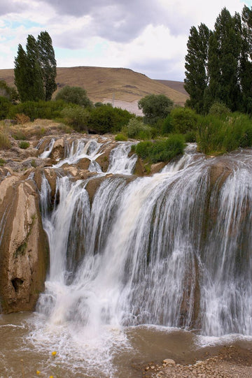 Multi-tiered waterfall cascading over rocks with green vegetation in Turkey, captured by Michael W. Rutherford.