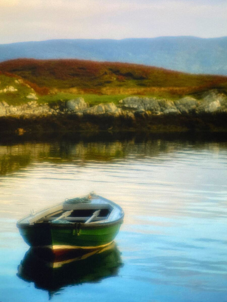 Serene green and white wooden rowboat by a tranquil lake, reflecting on water, captured by Michael W. Rutherford.