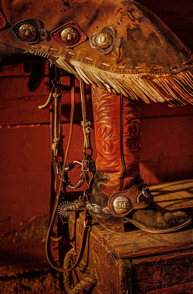 Artistic print of a cowboy's chap and boot detailing, set against a vintage red wood background – Collector’s Edition by Michael W. Rutherford.