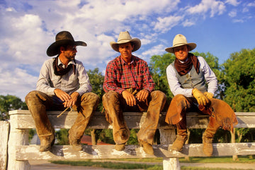 Photograph of three cowboys on a split rail fence, showcasing the serene spirit of the American West, by Michael W. Rutherford.