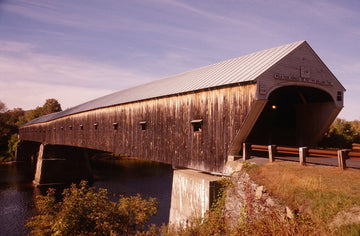 Photograph of the Cornish-Windsor Covered Bridge with autumn foliage reflecting in the Connecticut River.