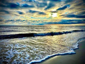 Serene ocean sunset at dusk with golden light reflecting on waves and clouds, captured by Michael W. Rutherford.